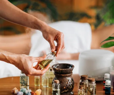 Hands pouring herbal oil among Ayurvedic oils and herbs at the clinic