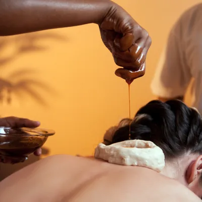 Warm medicated oil held on the neck during an Ayurvedic Basti treatment